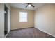 A bright, minimalist bedroom featuring neutral walls, carpet, a ceiling fan, and a built-in closet at 5638 N 61St Ln, Glendale, AZ 85301