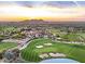 Expansive aerial view of a golf course community with vibrant greenery and mountain views at sunset at 6880 E Flat Iron Loop, Gold Canyon, AZ 85118