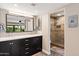 Modern bathroom with double vanity, a large mirror, and walk-in glass shower at 7937 E Solano Dr, Scottsdale, AZ 85250