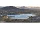 Scenic aerial view of a community lake nestled amongst homes and desert landscaping with mountains in the distance at 8857 S 167Th Ln, Goodyear, AZ 85338