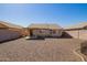 View of the home's gravel backyard with covered patio and perimeter fencing at 10792 W Elm Ln, Avondale, AZ 85323