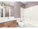 Bathroom with textured wallpaper, wooden vanity, and shower and tub combo at 10792 W Elm Ln, Avondale, AZ 85323