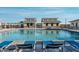 Community swimming pool featuring lounge chairs and a covered patio with seating near a residential building at 12125 W Levi Dr, Avondale, AZ 85323