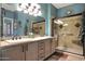 Bright bathroom featuring dual sinks, a spacious vanity, and modern tiled shower at 16017 W Wildflower Dr, Surprise, AZ 85374