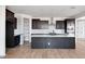 Modern kitchen features dark cabinets, an island, stainless steel appliances, and wood-look tile flooring at 16749 W Whispering Wind Dr, Surprise, AZ 85387