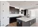 Bright kitchen featuring a large island, modern appliances, dark cabinets, and neutral tile backsplash at 16749 W Whispering Wind Dr, Surprise, AZ 85387