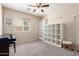 Bright bedroom featuring a ceiling fan, carpet floors, white shelves, and a piano against the wall at 17532 W Caribbean Ln, Surprise, AZ 85388