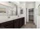 Bathroom featuring a double sink, spacious vanity, and a view into the walk-in closet at 18347 W Monte Lindo Ln, Surprise, AZ 85387