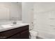 Modern bathroom with a dark vanity, a bath/shower combo and white fixtures at 18347 W Monte Lindo Ln, Surprise, AZ 85387