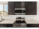 Close-up of kitchen featuring stainless steel oven, microwave, and dark cabinetry at 18347 W Monte Lindo Ln, Surprise, AZ 85387