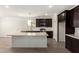 Bright kitchen featuring a spacious island, stainless steel appliances, and stylish dark cabinets at 18347 W Monte Lindo Ln, Surprise, AZ 85387