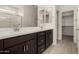 Bathroom featuring double sinks, dark wood cabinets, and a walk-in closet at 18363 W Monte Lindo Ln, Surprise, AZ 85387