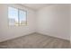 A sunlit bedroom with a large window and neutral carpet flooring at 18363 W Monte Lindo Ln, Surprise, AZ 85387