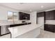 Modern kitchen featuring stainless steel appliances, quartz countertops, dark cabinetry, and natural light at 18363 W Monte Lindo Ln, Surprise, AZ 85387