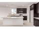 Modern kitchen featuring stainless steel appliances, a quartz island, dark cabinets, and ample storage at 18363 W Monte Lindo Ln, Surprise, AZ 85387