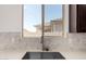 Close-up of the kitchen sink area, showcasing stone backsplash, quartz countertops, and a modern faucet at 18363 W Monte Lindo Ln, Surprise, AZ 85387