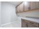 A laundry room featuring shaker cabinets and a light tile floor at 2121 W Sonoran Desert Dr # 47, Phoenix, AZ 85085