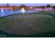 Lush green golf course with a blue flag and serene lake with illuminated fountain at 2369 E Fiesta Dr, Casa Grande, AZ 85194