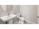 Stylish powder room with pedestal sink, modern faucet, and white toilet at 26650 W Siesta Ln, Buckeye, AZ 85396