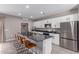 A modern kitchen features white cabinets, stainless steel appliances, and a gray countertop island with seating at 36728 N Alderney Ct, San Tan Valley, AZ 85143