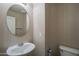 A half bathroom featuring a white toilet and sink below an oval mirror, perfect for guests at 3816 E Phelps St, Gilbert, AZ 85295