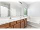 Bright bathroom featuring double sinks, a large mirror, and a soaking tub at 5625 W Euclid Ave, Laveen, AZ 85339