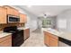 Kitchen with island, tile backsplash, black appliances, and adjacent living area at 5625 W Euclid Ave, Laveen, AZ 85339