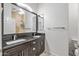 Bathroom with dark wood cabinets, black granite counters, and double sinks at 7329 W Tether Trl, Peoria, AZ 85383