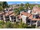 Aerial view of condominiums with red tile roofs surrounded by lush landscaping and palm trees against a mountain backdrop at 9445 N 94Th Pl # 212, Scottsdale, AZ 85258