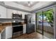 Modern kitchen with stainless steel appliances, granite counters, and a sliding glass door to the outside at 9445 N 94Th Pl # 212, Scottsdale, AZ 85258