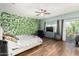 Relaxing bedroom with light hardwood floors, ceiling fan, and a leafy accent wall at 11121 N 165Th Ave, Surprise, AZ 85388