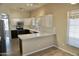 Bright kitchen featuring white cabinets, stainless steel appliances, breakfast bar, and herringbone tile backsplash at 11564 W Mule Deer Ct, Surprise, AZ 85378