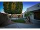 Landscaped backyard featuring manicured synthetic lawn, mature trees, and decorative rock ground cover at 12030 W Louise Ct, Sun City, AZ 85373