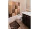 Cozy bathroom featuring tile floors, dark vanity, and shower with a brown patterned curtain at 12030 W Louise Ct, Sun City, AZ 85373