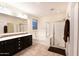 Bathroom featuring a tiled floor, large mirror, double vanity, and tiled shower and tub at 12030 W Louise Ct, Sun City, AZ 85373