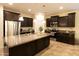 Modern kitchen featuring dark cabinets, granite countertops, stainless steel appliances, and large island at 12030 W Louise Ct, Sun City, AZ 85373