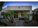 Charming covered patio with comfortable seating, decorative palm trees, and stucco exterior at 12030 W Louise Ct, Sun City, AZ 85373