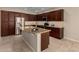 Kitchen featuring dark wood cabinets, stainless steel appliances, and a large island with granite countertops at 16390 W Sheila Ln, Goodyear, AZ 85395