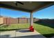 Landscaped backyard with a covered patio, brick wall, green lawn, and blue skies in the background at 17829 W Red Fox Rd, Surprise, AZ 85387