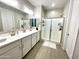 Bright bathroom features a double sink vanity, a glass enclosed shower, and wood look tile flooring at 17829 W Red Fox Rd, Surprise, AZ 85387