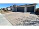 Home featuring a gray exterior, gray garage doors, a paved driveway, and desert landscaping at 17829 W Red Fox Rd, Surprise, AZ 85387