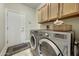 A functional laundry room features overhead cabinets, a side entry door, and a modern washer and dryer at 18102 N Petrified Forest Dr, Surprise, AZ 85374