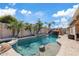 Inviting backyard pool area with mature palm trees, rock waterfall feature, and blue skies at 21921 E Domingo Rd, Queen Creek, AZ 85142