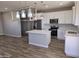 Open kitchen featuring white cabinets, stainless steel appliances, and a center island with wood flooring at 26409 W Desert Crest St, Casa Grande, AZ 85193