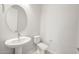 Modern powder room featuring a pedestal sink, round mirror, and neutral paint at 26664 W Siesta Ln, Buckeye, AZ 85396