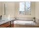 Bright bathroom featuring a soaking tub, tile surround, and a large window at 27000 N Alma School Pkwy # 1032, Scottsdale, AZ 85262