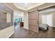 Open bedroom featuring a sliding barn door and neutral decor, adjacent to the living space at 27000 N Alma School Pkwy # 1032, Scottsdale, AZ 85262