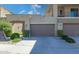 Attached two-car garage with neutral doors, stone accents, and landscaping providing curb appeal at 27000 N Alma School Pkwy # 1032, Scottsdale, AZ 85262