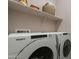 Efficient laundry room featuring modern Whirlpool washer and dryer units with shelving for storage at 37765 W Santa Maria St, Maricopa, AZ 85138