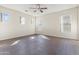 Bright bedroom featuring hardwood floors, ceiling fan, and ample natural light from multiple windows at 3911 S 100Th Gln, Tolleson, AZ 85353